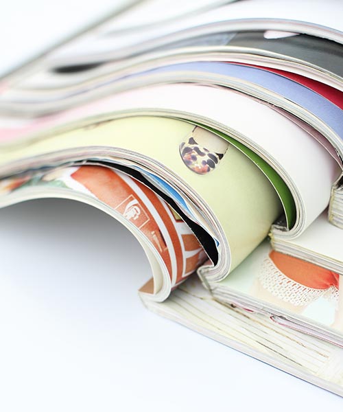 A stack of colorful, glossy magazines with curved pages.
