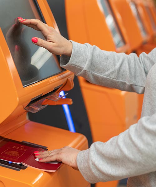 A person using a self-service terminal by placing a passport on the scanner and interacting with the touchscreen.
