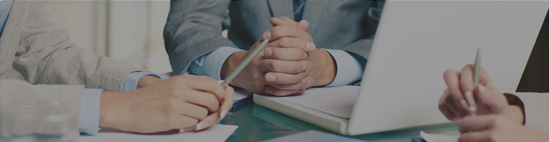 Person working at a desk with keyboard, mouse, and laptop