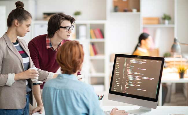 Entwicklerteam arbeitet gemeinsam an maßgeschneiderter Software am Computer.