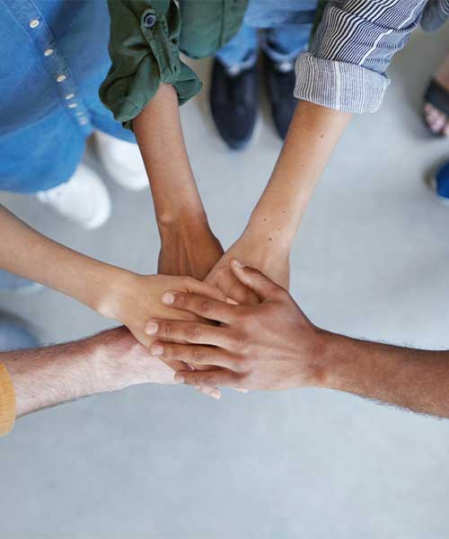 Fünf aufeinandergelegte Hände zur symbolischen Darstellung von Teamarbeit